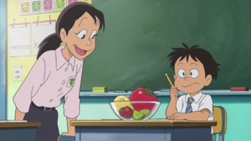 Sala de aula com uma professora sorrindo para Joãozinho, que está sentado em sua carteira com um olhar pensativo. Na frente dele, uma tigela de frutas com um tomate claramente incluído, criando uma cena divertida.